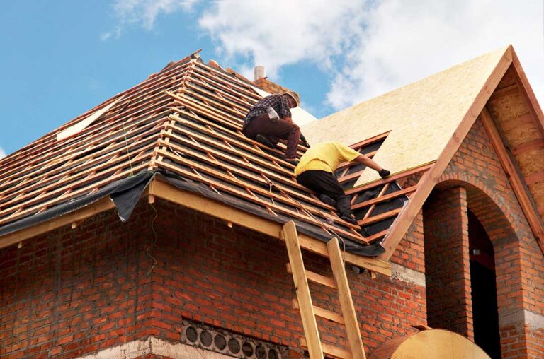 Homeowner inspecting roof shingles and clearing leaves from a gutter before a severe storm