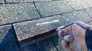 Homeowner reviews roof warranty papers beside a table with roof photos and maintenance records.